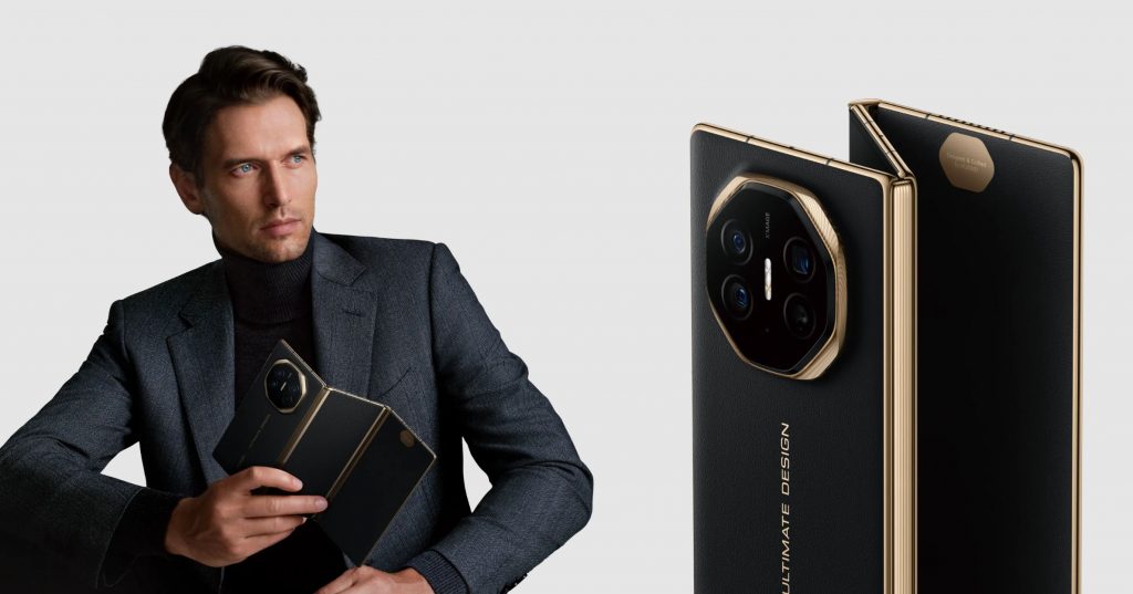 Homme en costume tenant un smartphone pliable noir avec finitions dorées.