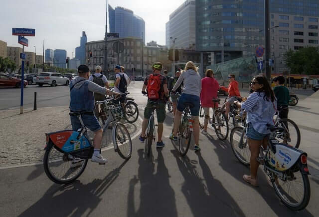 Groupe de cyclistes en ville près de grands immeubles modernes, participant à une balade urbaine.
