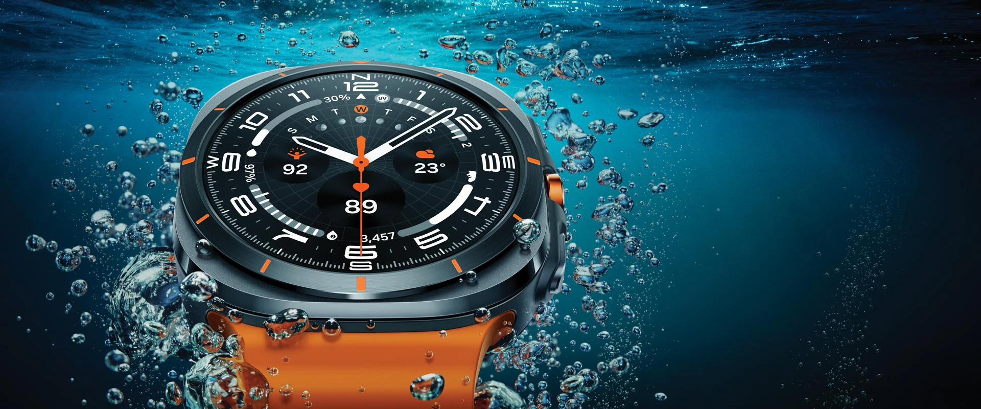 galaxy watch sous l'eau avec cadran lumineux et bracelet orange, entourée de bulles.